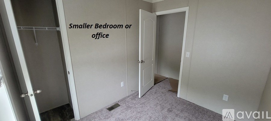 A room with a door and a wall with a sign that says "Smaller Bedroom or office".
