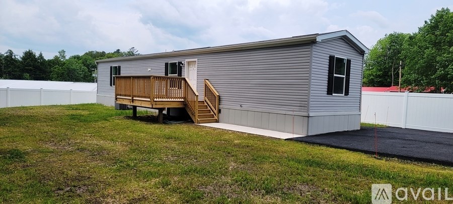 A small house with a deck and a porch is available for rent.