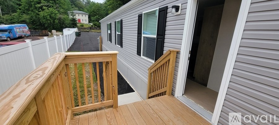 A grey house with a wooden deck and a white fence.