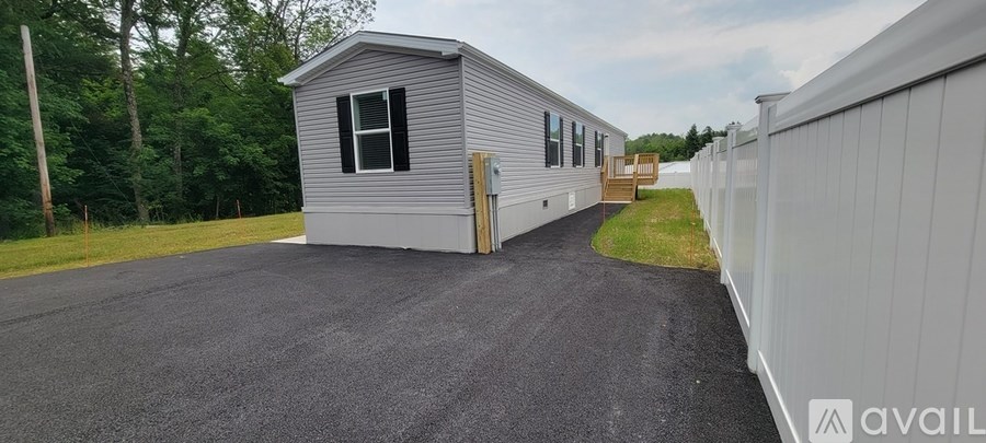 A grey mobile home with a white fence in front.