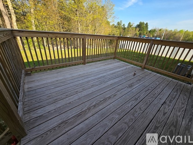 A wooden deck with a railing and a view of trees.