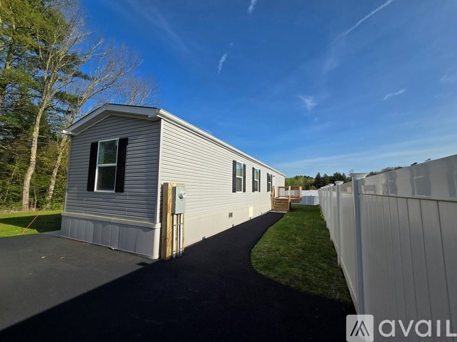 A mobile home with a grey siding and a white fence.