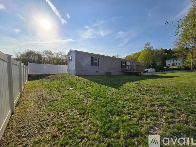 A sunny day at a grassy field with a building and a white house in the background.