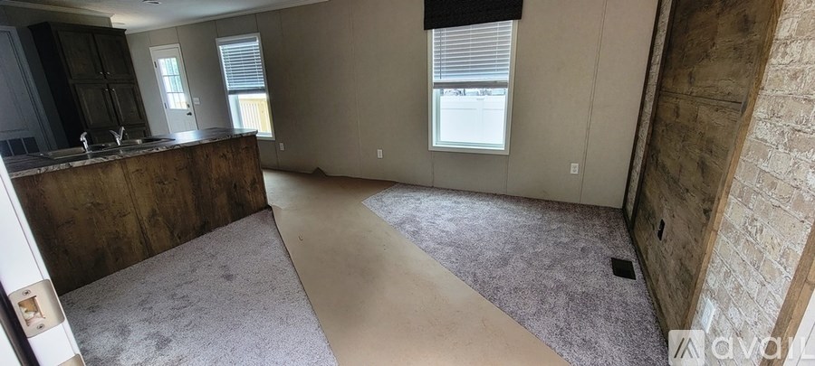A room with a brown counter and a window with blinds.