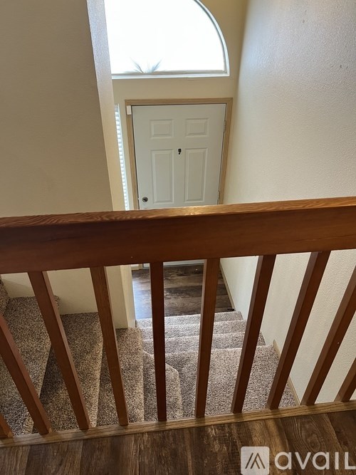 A white door is in a small room with a wooden staircase leading to it.