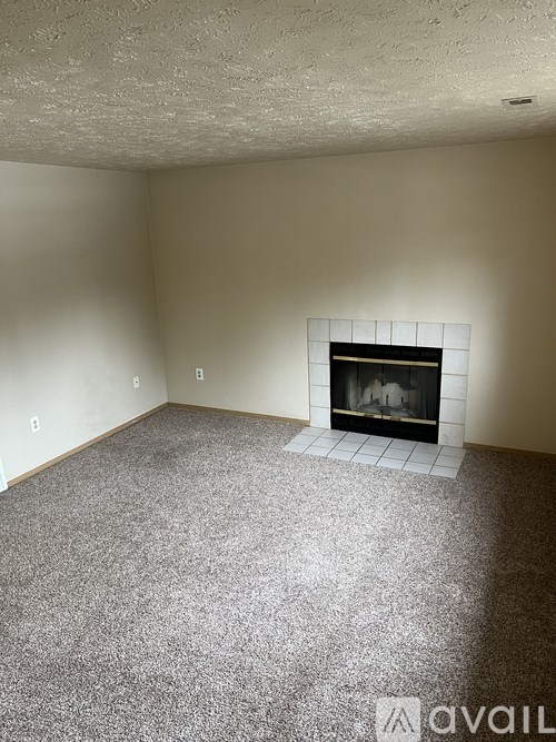 A living room with a fireplace and carpeted floor.