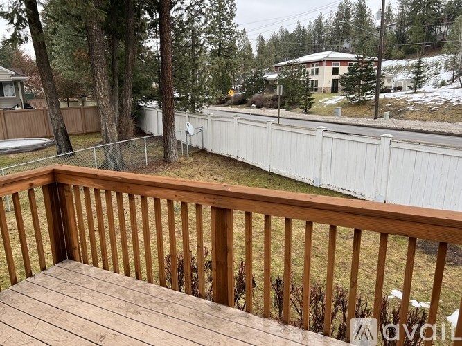 A deck with a white fence and trees in the background.