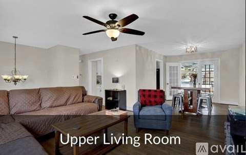 A living room with a brown couch and a ceiling fan.