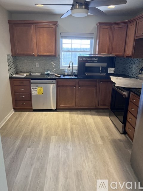 A kitchen with wooden cabinets and a stainless steel dishwasher.