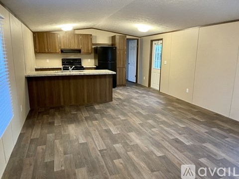A kitchen with wooden cabinets and a black refrigerator.