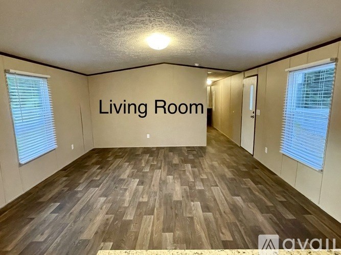 A living room with wooden flooring and white walls.