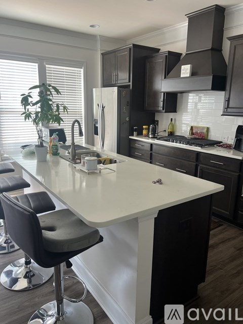 A kitchen with a white island and black bar stools.