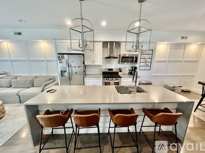 A modern kitchen with a large island and chairs.