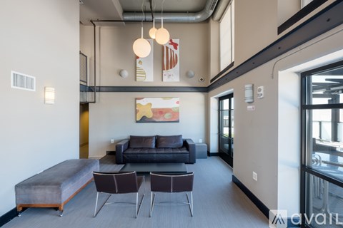 A living room with a grey couch and a painting on the wall.