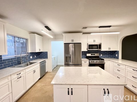 A kitchen with white cabinets and a marble countertop.