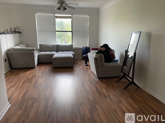 A room with wooden flooring and a person sitting on a couch.