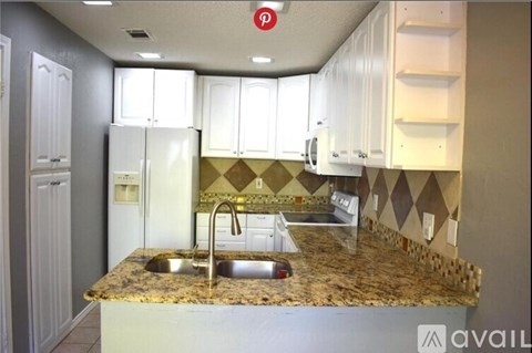 A kitchen with granite countertops and white cabinets.
