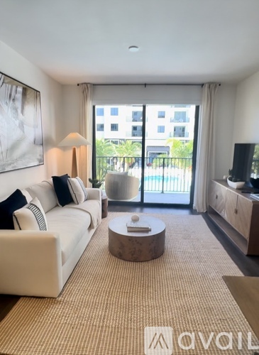 A living room with a white couch and a coffee table in front of a large window.