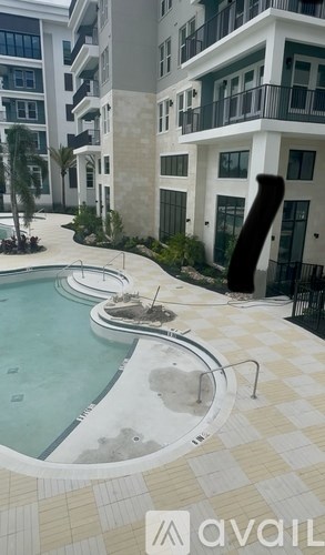 A pool area with a hot tub and a building in the background.