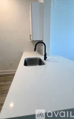 A white kitchen counter with a sink and a black faucet.
