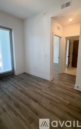 A room with wooden flooring and a window overlooking a cityscape.