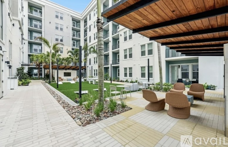 A patio area with chairs and a palm tree in front of apartment buildings.