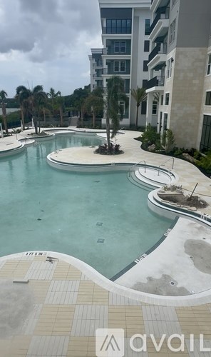 A large outdoor swimming pool with a tiled edge and a small fountain in the middle.