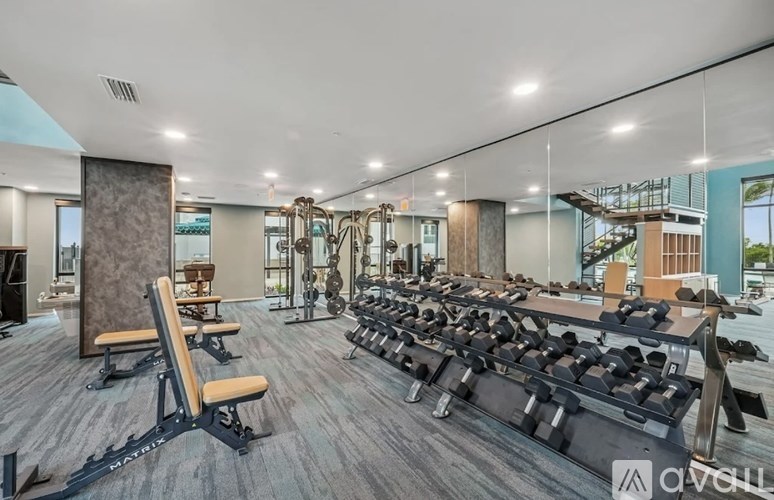 A tall white building with balconies and a palm tree in front.