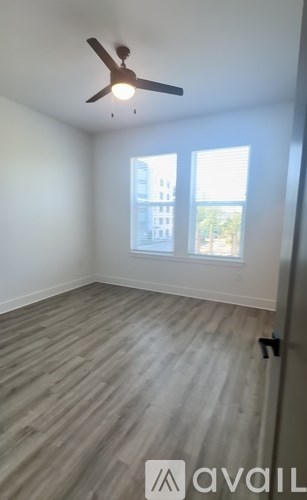 A room with a ceiling fan and wooden flooring.