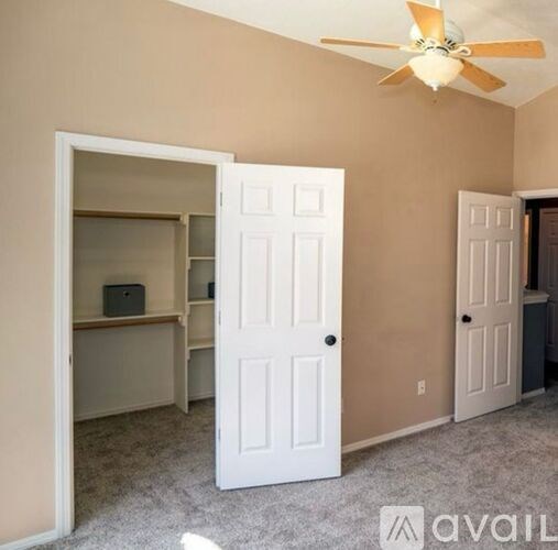 A room with a white door and a ceiling fan.