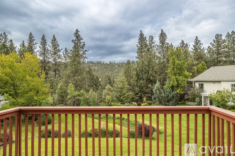 A house with a brown fence in front of a forest.