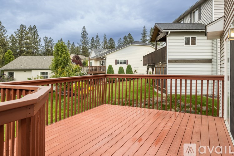 A wooden deck with a railing and a house in the background.