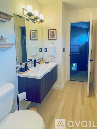 A bathroom with a toilet, sink, and mirror.