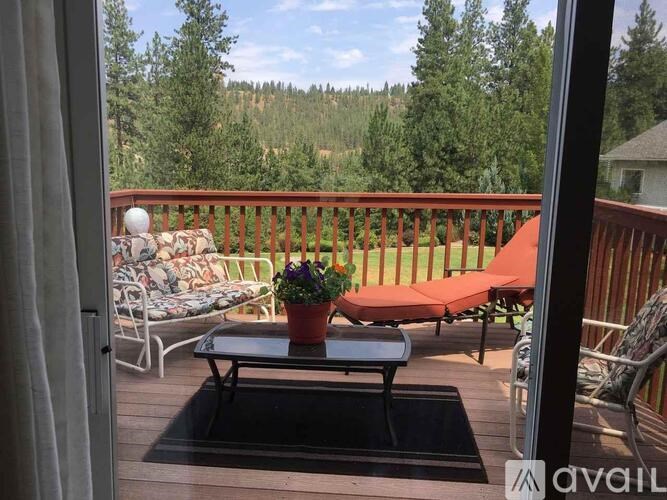 A balcony with a table, chairs, and a view of the forest.