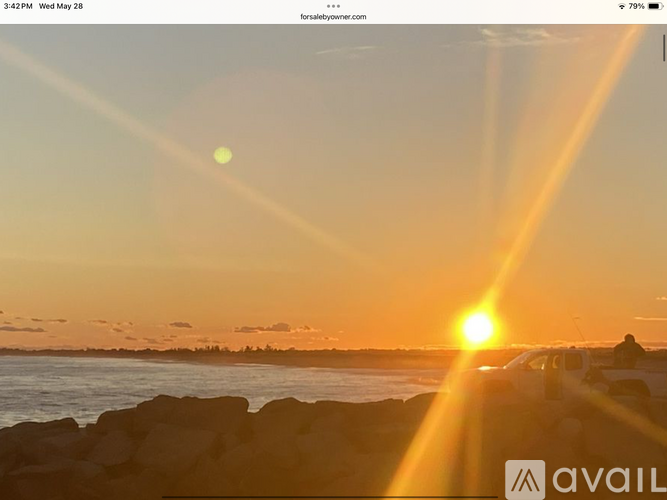 A sunset scene with a bright sun and a person standing on the shore.