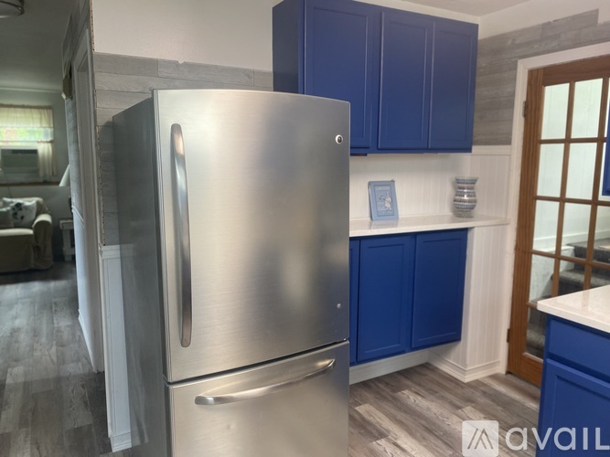 A stainless steel refrigerator in a kitchen with blue cabinets.