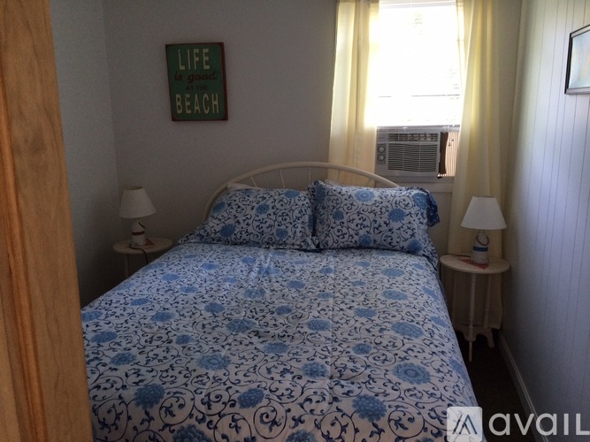 A bedroom with a bed, two lamps, and a framed picture on the wall.