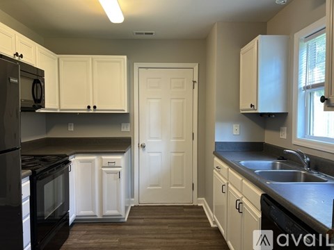 A kitchen with white cabinets and black appliances.