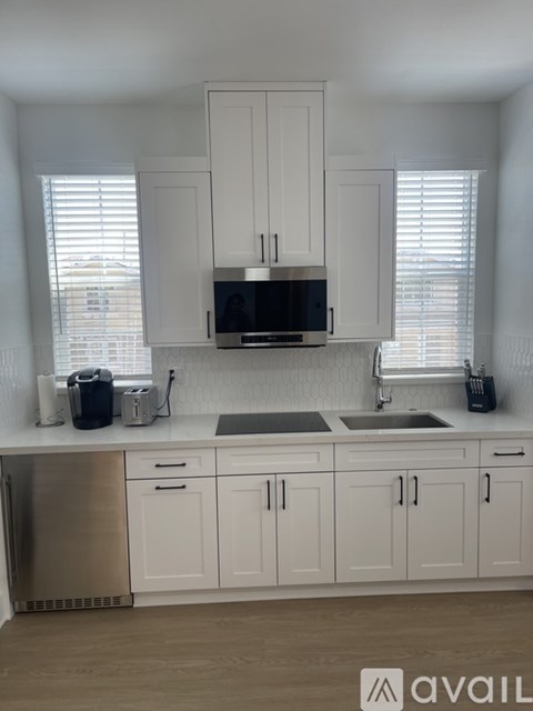 A kitchen with white cabinets and a stainless steel refrigerator.