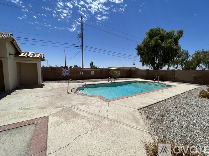A pool surrounded by a concrete patio and a house.
