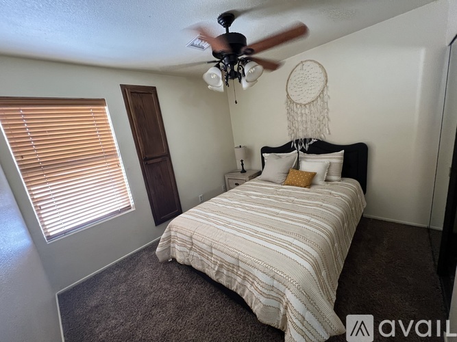A bedroom with a bed, a ceiling fan, and a window with blinds.