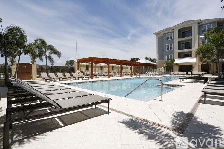 A pool area with sun loungers and a building in the background.