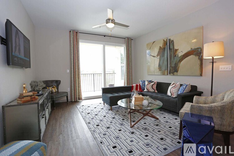 A living room with a black couch, a coffee table, and a painting on the wall.