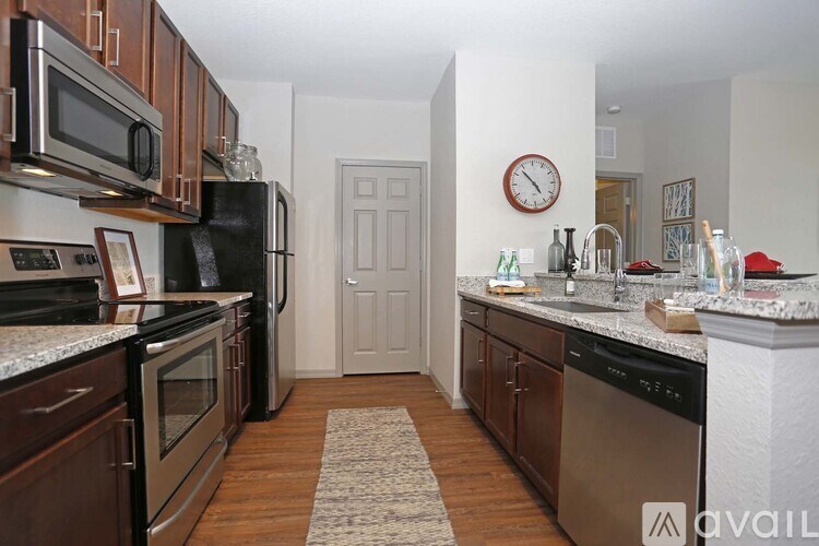 A kitchen with a refrigerator, microwave, oven, and sink.