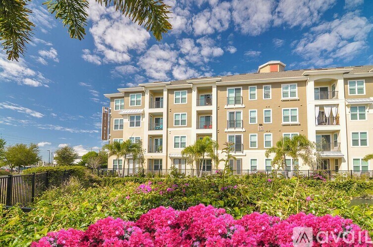 A row of apartment buildings with a fence and flowers in front.