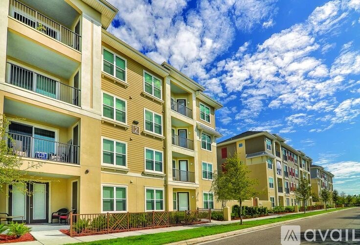 A row of modern apartment buildings with balconies and greenery in front.