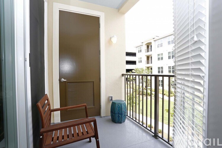 A balcony with a wooden chair and a blue vase.
