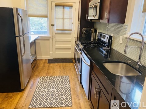 A kitchen with a black fridge and a black stove top.