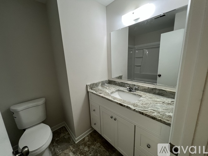 A bathroom with a toilet, sink, and mirror.