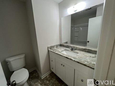 A bathroom with a toilet, sink, and mirror.